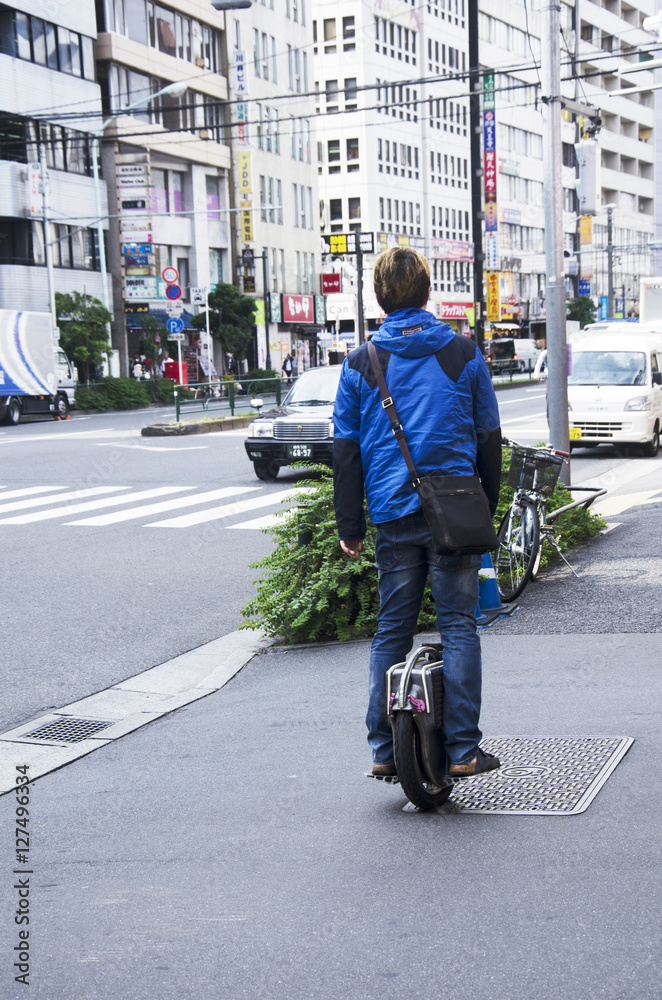 Japanese people standing and riding unicycle  on pathway beside