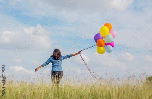 Beautiful Girl jumping with balloons on the beach