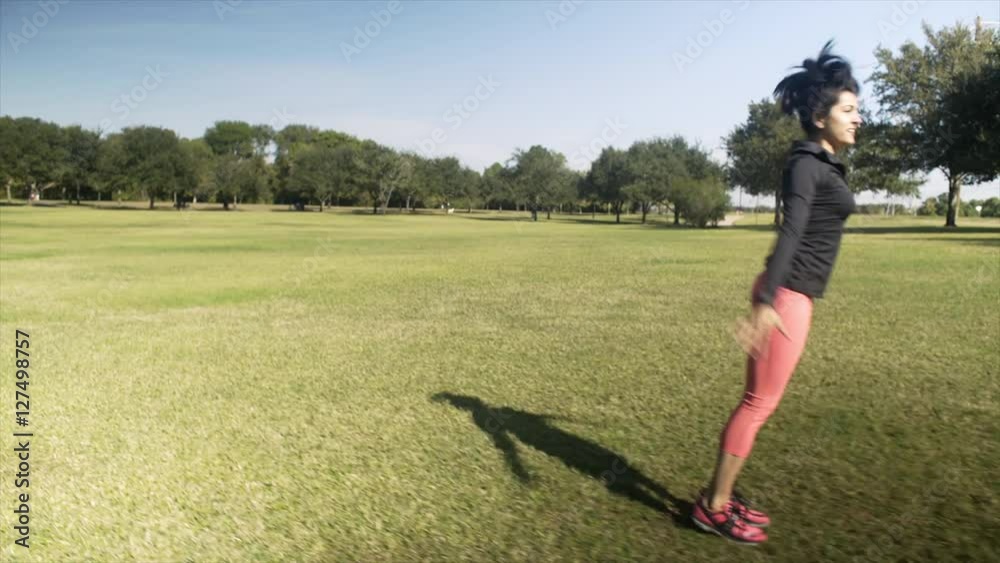 A women playfully does a cartwheel or round off on a bright sunny morning in the park A women playfully does a cartwheel or round off on a bright sunny morning in the park