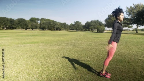 A women playfully does a cartwheel or round off on a bright sunny morning in the park