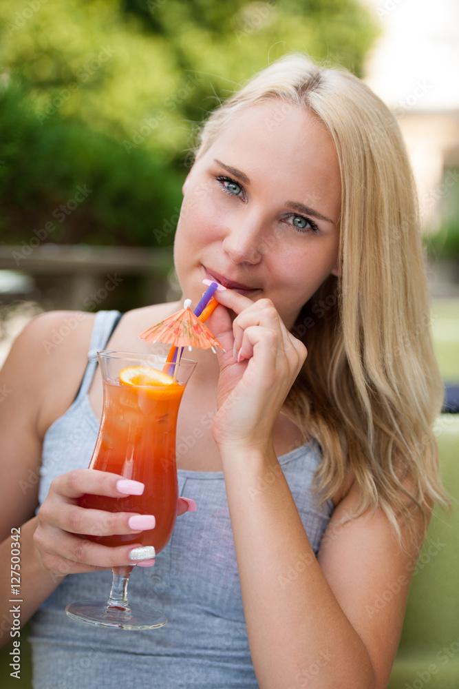 young woman drinks cocktail outdoor on a hot summer afternoon in young woman drinks cocktail outdoor on a hot summer afternoon in