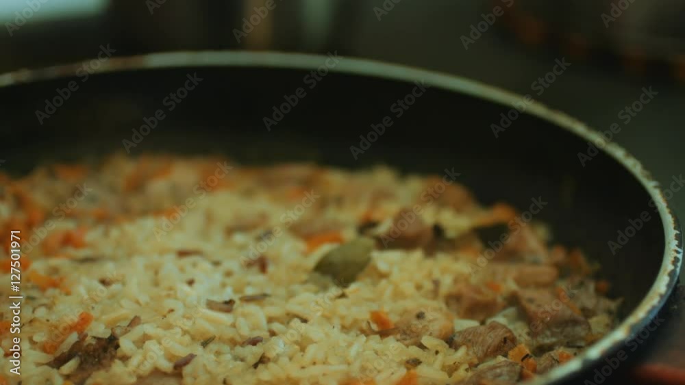 Dish of rice with meat cooked on frying pan, panoramic close-up view. Dish of rice with meat cooked on frying pan, panoramic close-up view.