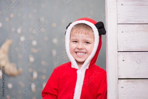 Улыбающийся маленький мальчик в рождественском красном костюме