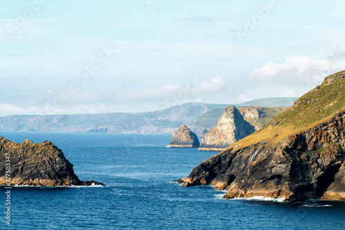 Landscape the land of King Arthur and the Tintagel castle ruins. Summer blue sky with clouds over the ocean view and coastline cliffs