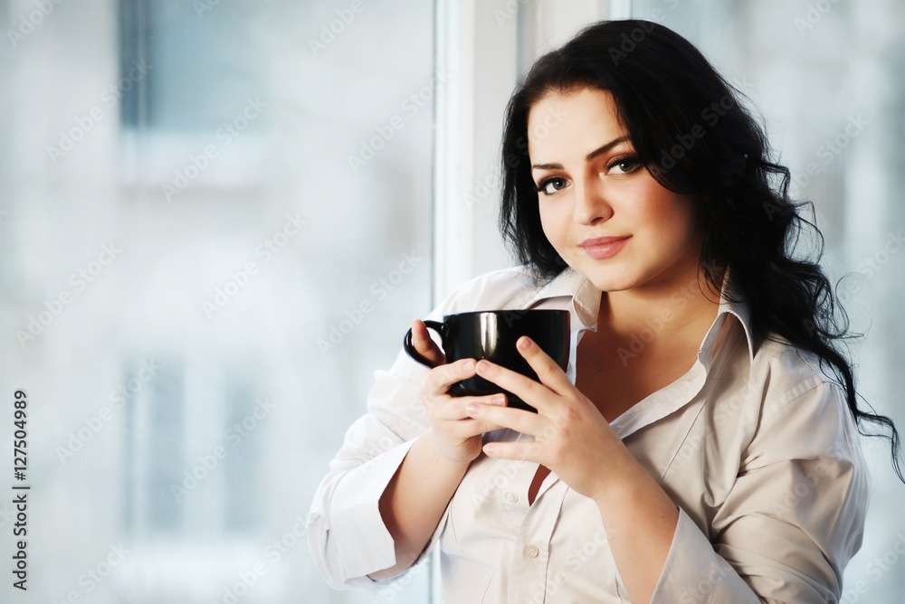 Portrait of young woman holding a cup of coffee.