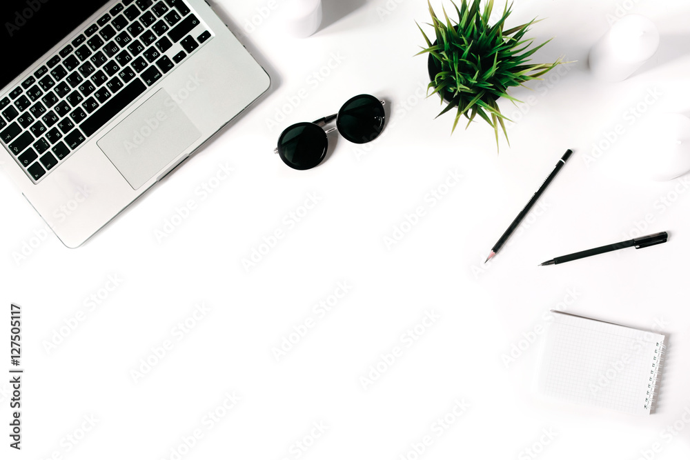 Stylish minimalistic workplace with laptop keyboard and notebook and sunglasses in flat lay style. White background. Top view. Stylish minimalistic workplace with laptop keyboard and notebook and sunglasses in flat lay style. White background. Top view.