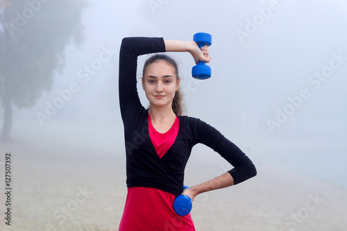 Young sporty woman exercises with dumbells during fitness traini photo