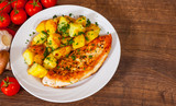 Grilled chicken breast with potato in a plate on wooden table. top view