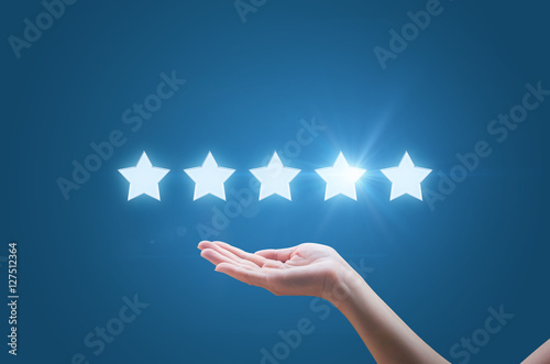 Businesswoman hand holding five stars isolated on blue background