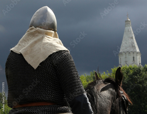 Horseman in armor on a background of church and stormy sky