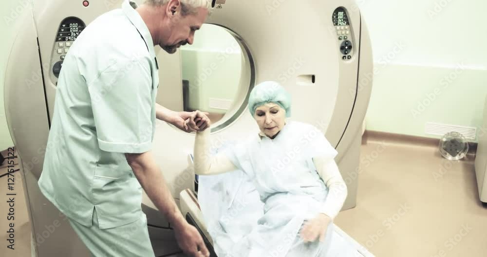 Doctor helps elderly woman to use CT MRI scanning 4k video. female patient lies on computed tomography scanner in diagnostic clinic Doctor helps elderly woman to use CT MRI scanning 4k video. female patient lies on computed tomography scanner in diagnostic clinic