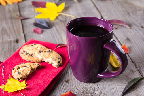 Cup of coffee surounded by red, purple and yellow fall leaves