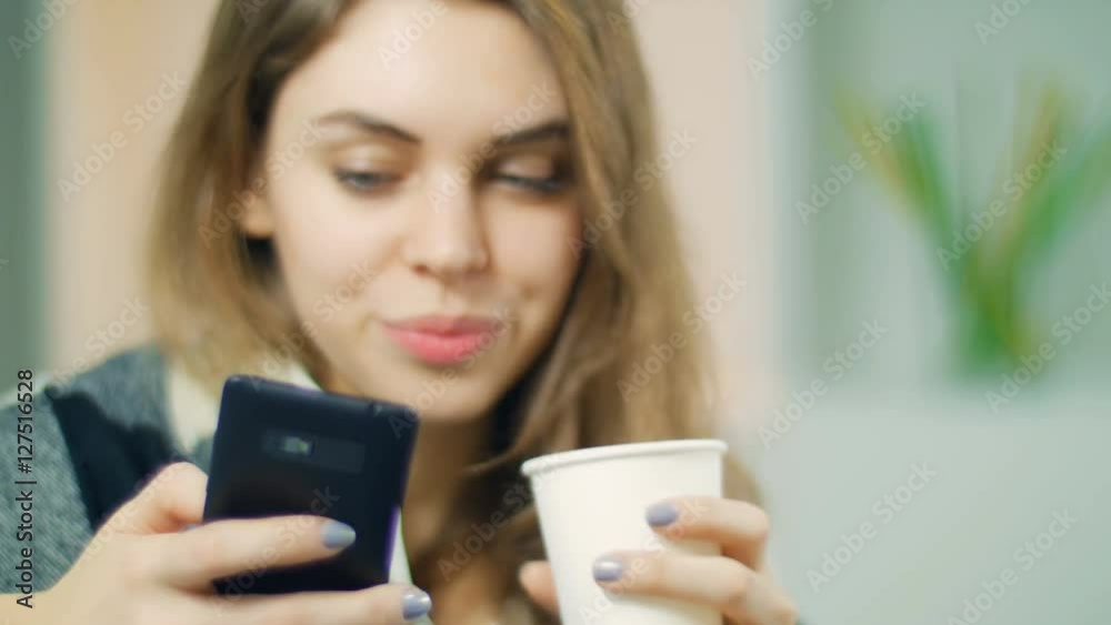 The young girl communicates by phone and has tea The young girl communicates by phone and has tea