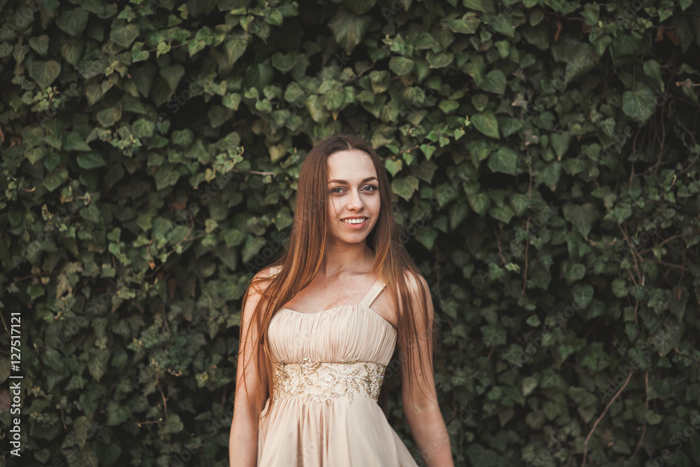 Beautiful girl, model near the wall of leaves and bushes in park Beautiful girl, model near the wall of leaves and bushes in park