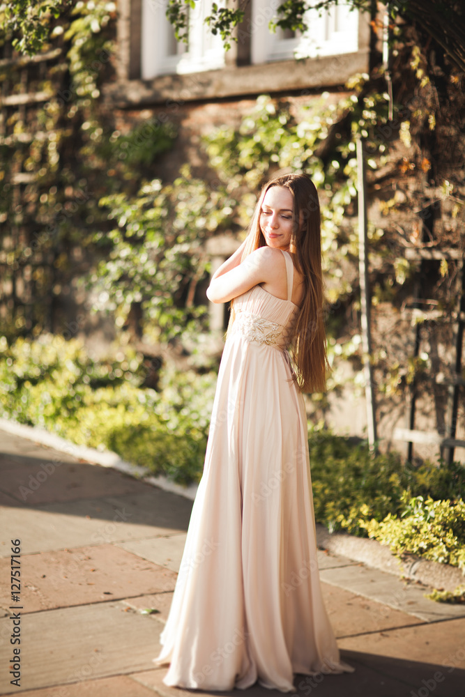 Attractive young woman with long dress enjoying her time outside in park sunset background Attractive young woman with long dress enjoying her time outside in park sunset background