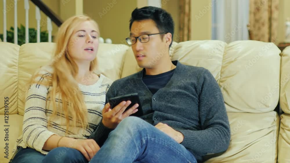 Young multi-ethnic couple spends time at home. enjoy tablet Young multi-ethnic couple spends time at home. enjoy tablet