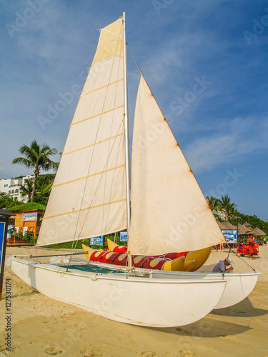 white Catamaran with sails on white sand