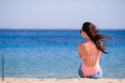Young beautiful woman with coffee on the beach during tropical vacation. Girl enjoy her wekeend on one of the beautiful beaches in Mykonos, Greece, Europe.