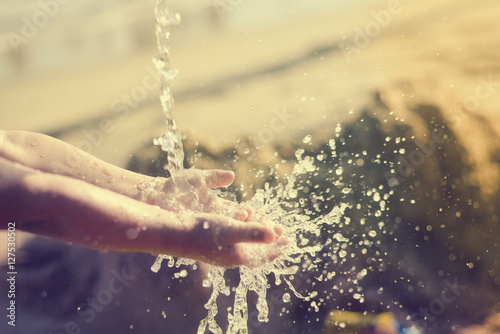 Happy child holding hands in water. Summer outdoors background