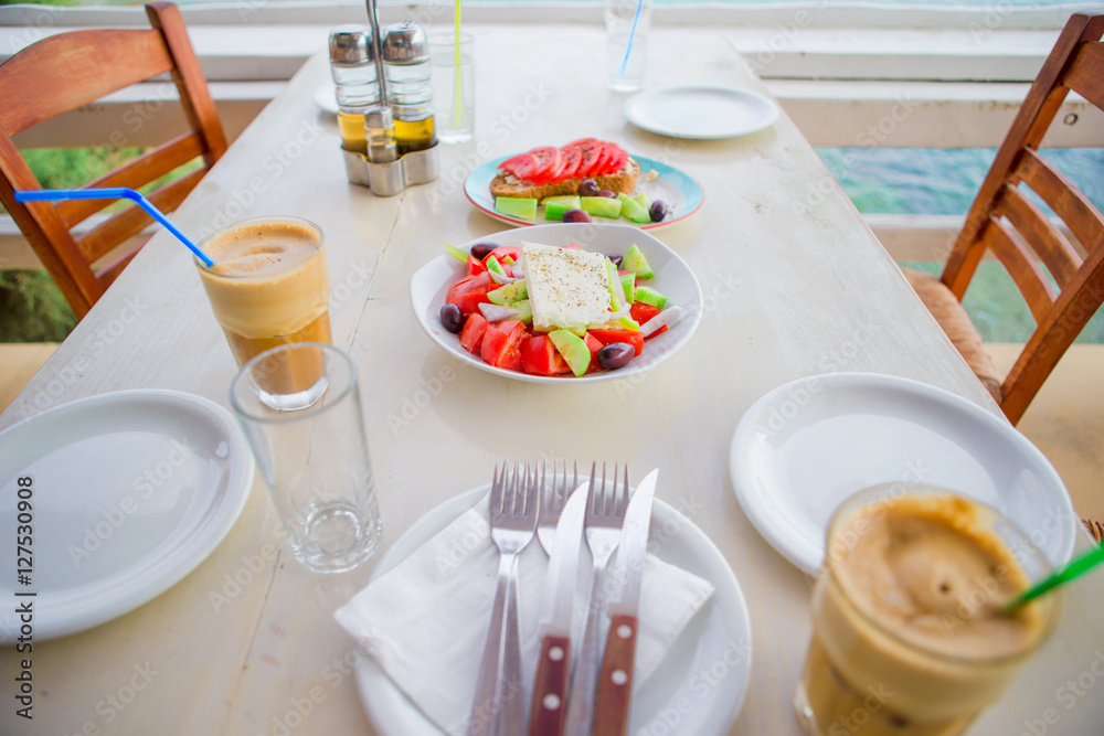 Traditional lunch with delicious fresh greek salad and brusketa served for lunch at outdoor restaurant with beautiful view on the sea and port Traditional lunch with delicious fresh greek salad and brusketa served for lunch at outdoor restaurant with beautiful view on the sea and port