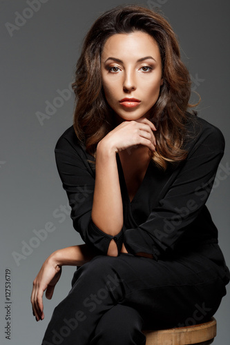 Young beautiful woman looking at  camera sitting over grey background.