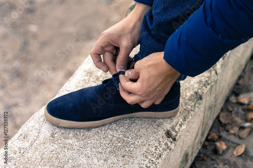 young man tying shoelaces on blue sneakers