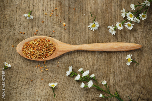 Bee pollen with wooden spoon and flower