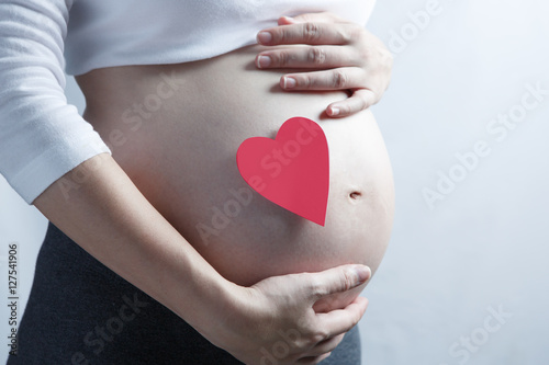 Wallpaper Mural Pregnant woman with single red heart on her baby bump. All on wh Torontodigital.ca