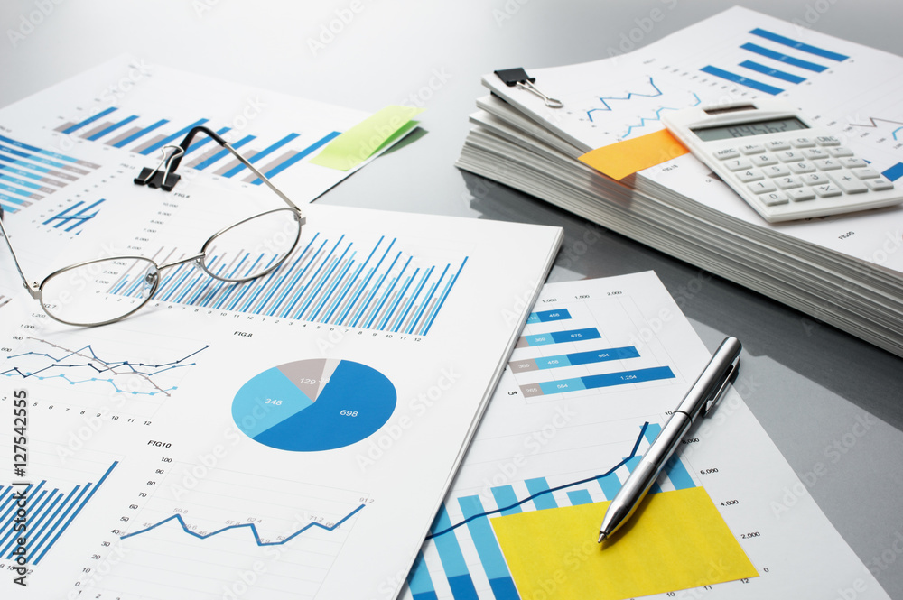 Preparing report. Blue graphs, glasses, calculator and pen. Business reports and pile of documents on gray reflection background.
Preparing report. Blue graphs, glasses, calculator and pen. Business reports and pile of documents on gray reflection background.
