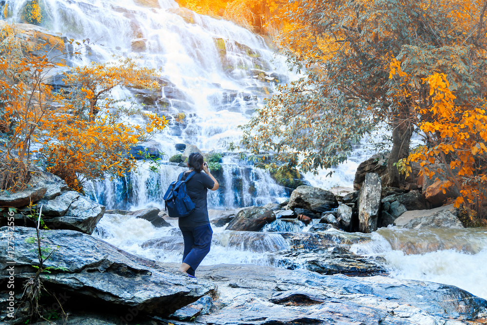 The tourist take photo waterfall in rainforest at Thailand.. The tourist take photo waterfall in rainforest at Thailand..