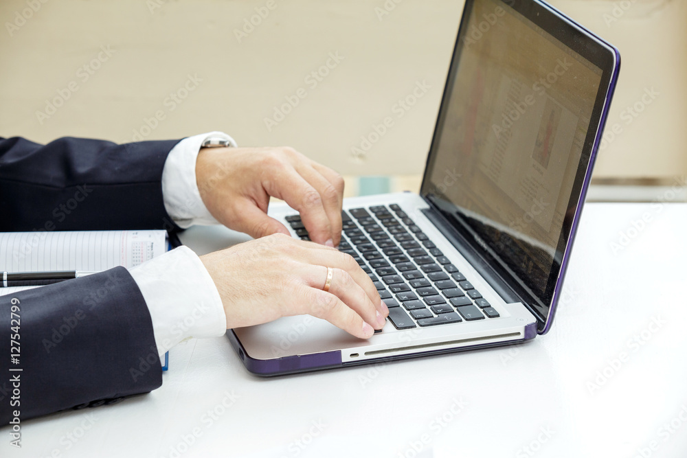 Businessman typing on a laptop. The man in a suit and a white shirt. Closeup. Businessman typing on a laptop. The man in a suit and a white shirt. Closeup.