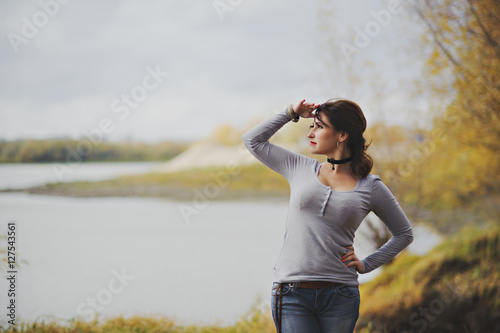 Young beautiful woman stands on the shore and looks into the distance, autumn.
