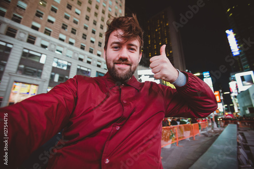 Cute funny man taking selfie on Times Square at night, Manhattan. Inspiring New York atmosphere and a handsome bearded hipster