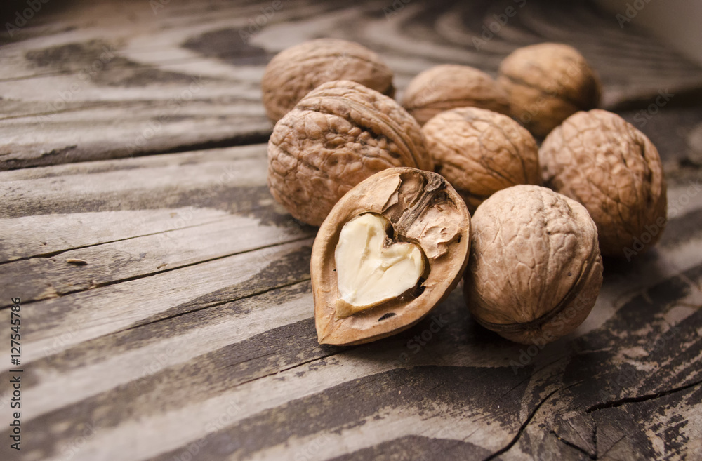 Walnuts on a grey textured wooden table. Assortment of nuts isolated on rustic old wooden background and splintered walnut with heart-shaped core. Walnuts close up Walnuts on a grey textured wooden table. Assortment of nuts isolated on rustic old wooden background and splintered walnut with heart-shaped core. Walnuts close up