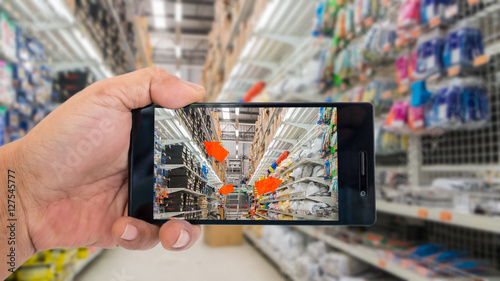 Augmented reality application for retail business concept. Hand holding smart phone with A/R application on screen to finding interested product in construction depot.