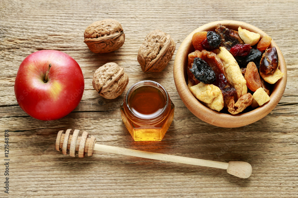 Bowl of dried fruits, red apple, nuts and jar of honey on wood Bowl of dried fruits, red apple, nuts and jar of honey on wood
