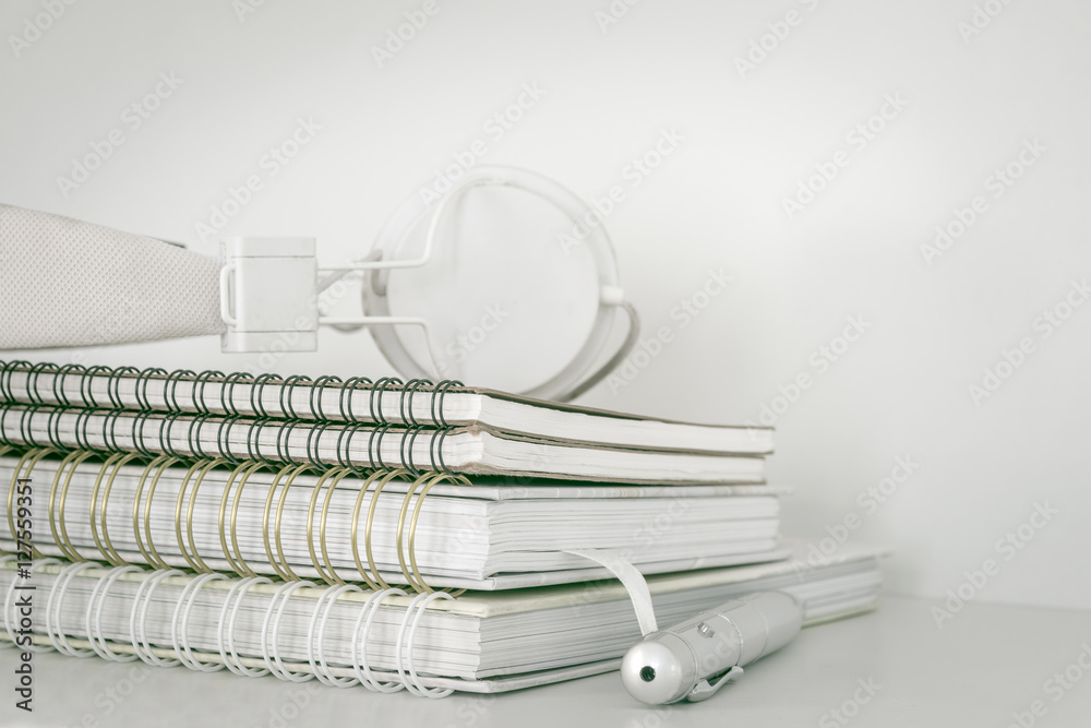 Stack of four notebooks and pen on white background. Earphone on top of stack notebook Stack of four notebooks and pen on white background. Earphone on top of stack notebook