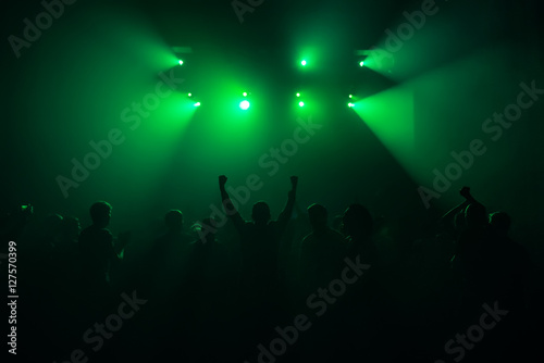silhouettes of hands on concert in front of bright stage lights