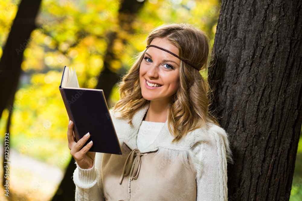Obraz premium Beautiful boho girl enjoys reading book in the park.
