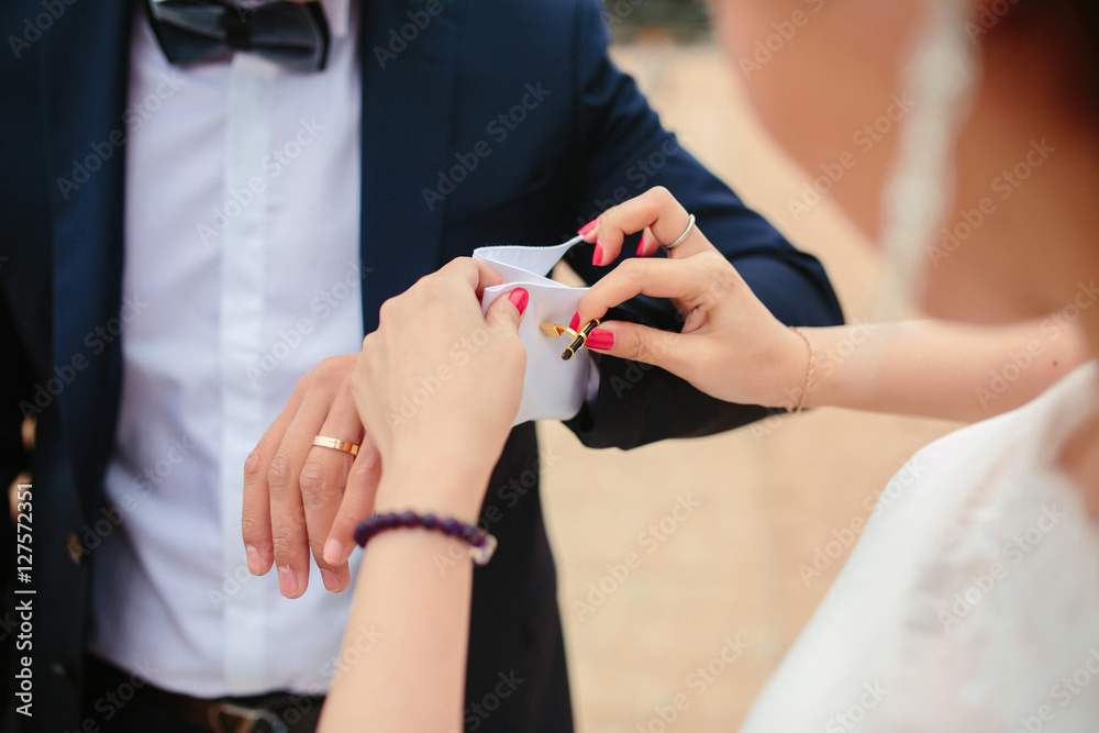 Preparations for the wedding, the bride helps the groom to wear cufflinks