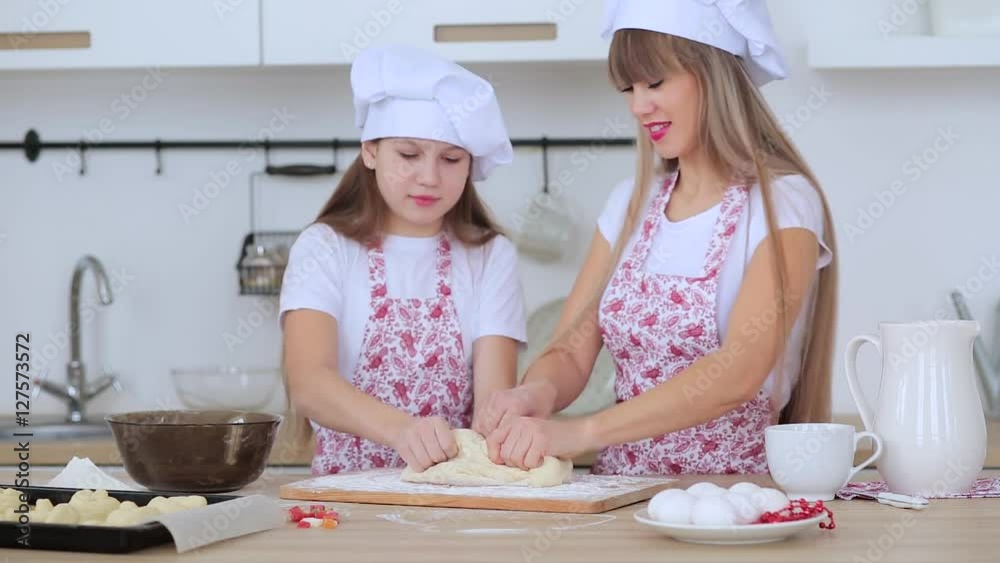 Mother and daughter in hats and aprons to cook scones for Christmas Mother and daughter in hats and aprons to cook scones for Christmas