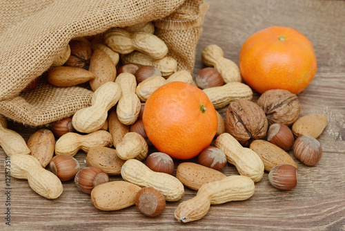 Nüsse und Mandarinen auf Holz mit Jute Beutel photo
