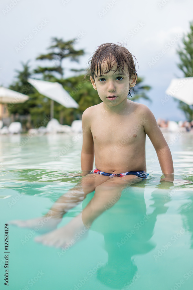 Young boy kid child splashing in swimming pool having fun leisur