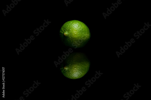 One whole green lime isolated on black background
