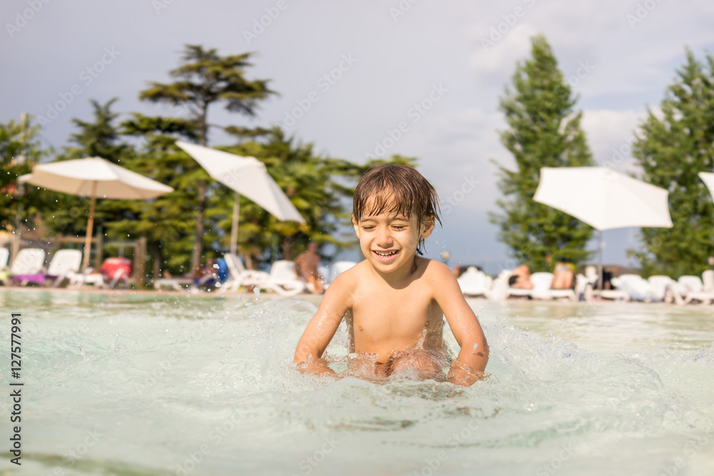 Young boy kid child splashing in swimming pool having fun leisur Young boy kid child splashing in swimming pool having fun leisur