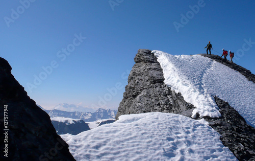 mountain guide and clients on a high alpine summit in the Swiss Alps