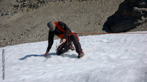 mountain guide demonstrating a crevasse rescue on a glacier in the Swiss Alps photo