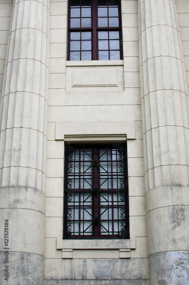 Two windows between two white pillars. White wall and white pillars.
