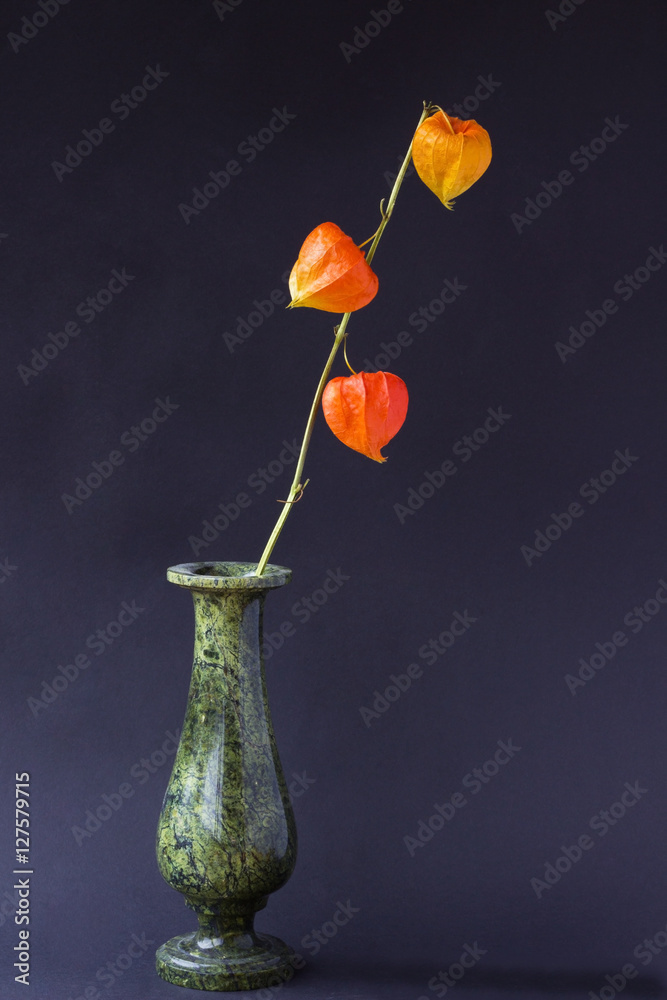 Obraz premium Orange flowers in a green vase on black background
