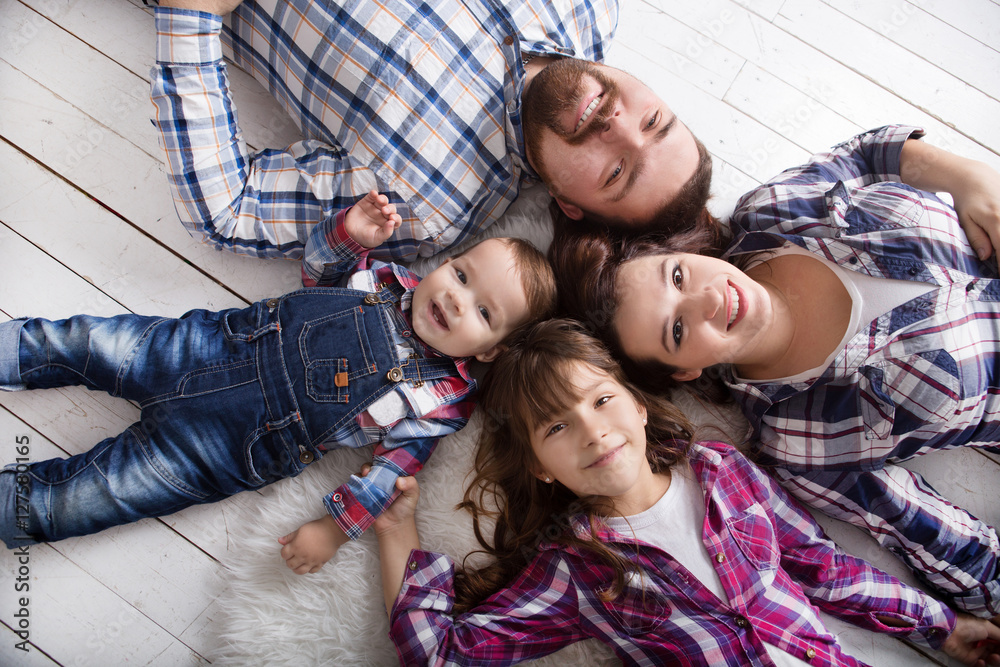 happy family mother, father and two children playing and cuddling at home on floor

